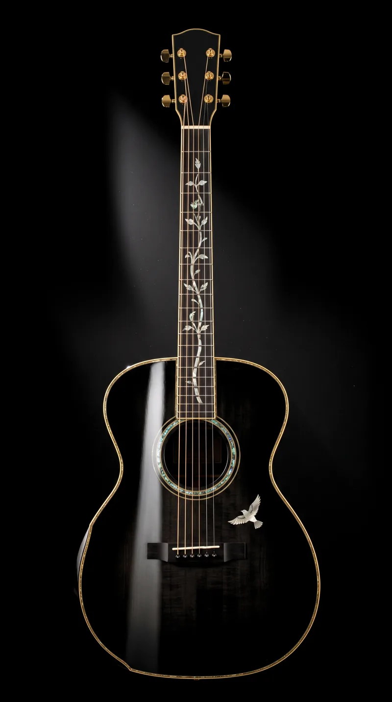 A jet-black grand-concert guitar standing upright against pure black under one hard light, a full mother-of-pearl tree of life running the length of its fingerboard and a pearl bird in flight on its lower bout.
